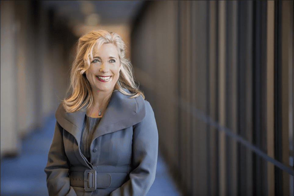 A woman in a blue coat smiling for the camera.